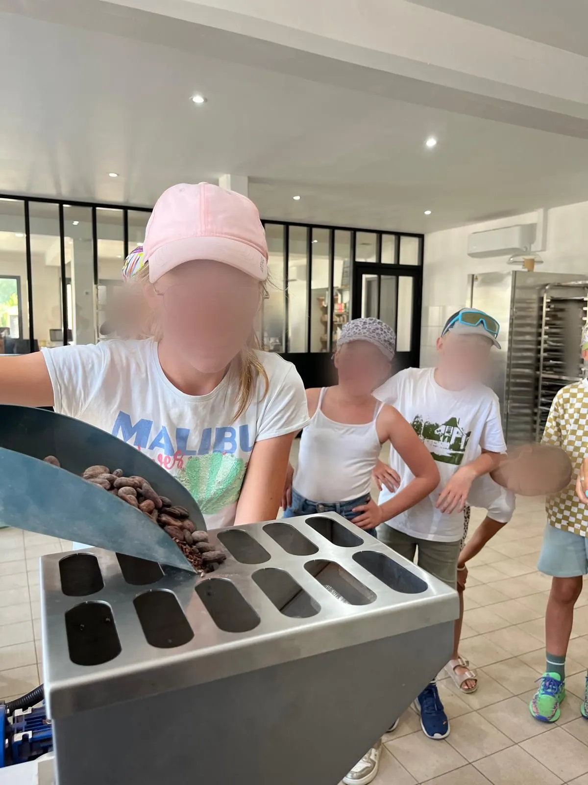 Une enfant verse des fèves de cacao dans une machine du laboratoire de la chocolaterie
